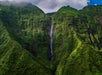 A waterfall flowing down a vegetation covered cliffside on the Kauai Eco Adventure Helicopter Tour in Hawaii USA.