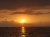 Golden sunset over the ocean with clouds in the background, seen from a Na Pali Coast sunset cruise.
