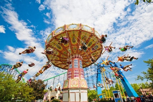 View looking up at the Wave Swinger ride in motion with people enjoying the right on a sunny day at Kennywood.