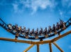 A rollercoaster car full of people on a dip on the Steel Curtain Steelers ride, with some raising their hands in excitement.