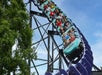 A rollercoaster car full of people enjoying the light blue and purple Phantom's Revenge coaster on a beautiful day at Kennywood.