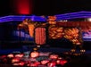 Illuminated jack-o'-lantern display shaped like a horse and rider, surrounded by smaller carved pumpkins, with colorful lights in the background.