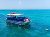 A boat anchored in clear blue water with people snorkeling nearby.
