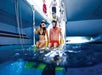 Two people in swimwear and snorkeling masks sit at the edge of a boat, preparing to enter the water.