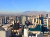 Aerial view of Las Vegas skyline with numerous high-rise buildings, mountains in the background, and clear blue sky.