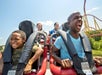 A father and son sitting at the front of a coaster smiling and screaming as they ride at Kings Dominion in Doswell, Virginia.