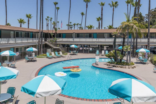 Relaxing outdoor pool with lounge chairs, tables and umbrellas.