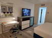 Guest room with a work desk and chair, flat-screen TV, and a mini fridge.
