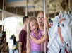 A mother and he daughter riding a carousel and laughing  at King's Island in Cincinnati, Ohio.