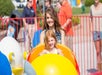 A mother and daughter smiling while riding Snoopy's Space Buggies at King's Island in Cincinnati, Ohio.