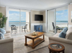 Living room with sofa bed, flat-screen TV, two balconies, and ocean view.