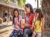 A mother with her two daughters sitting down having a snack at Knott's Berry Farm in Buena Park, California.