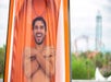 A man going down an orange water slide while smiling at Knott's Soak City Water Park in Los Angeles, California.