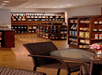 A small store with shelves stocked with various packaged goods and beverages, wicker chairs around a glass table, and warm lighting.