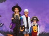 Three children in Halloween costumes—a witch, a scientist, and a pirate—stand in front of a purple background holding trick-or-treat bags.