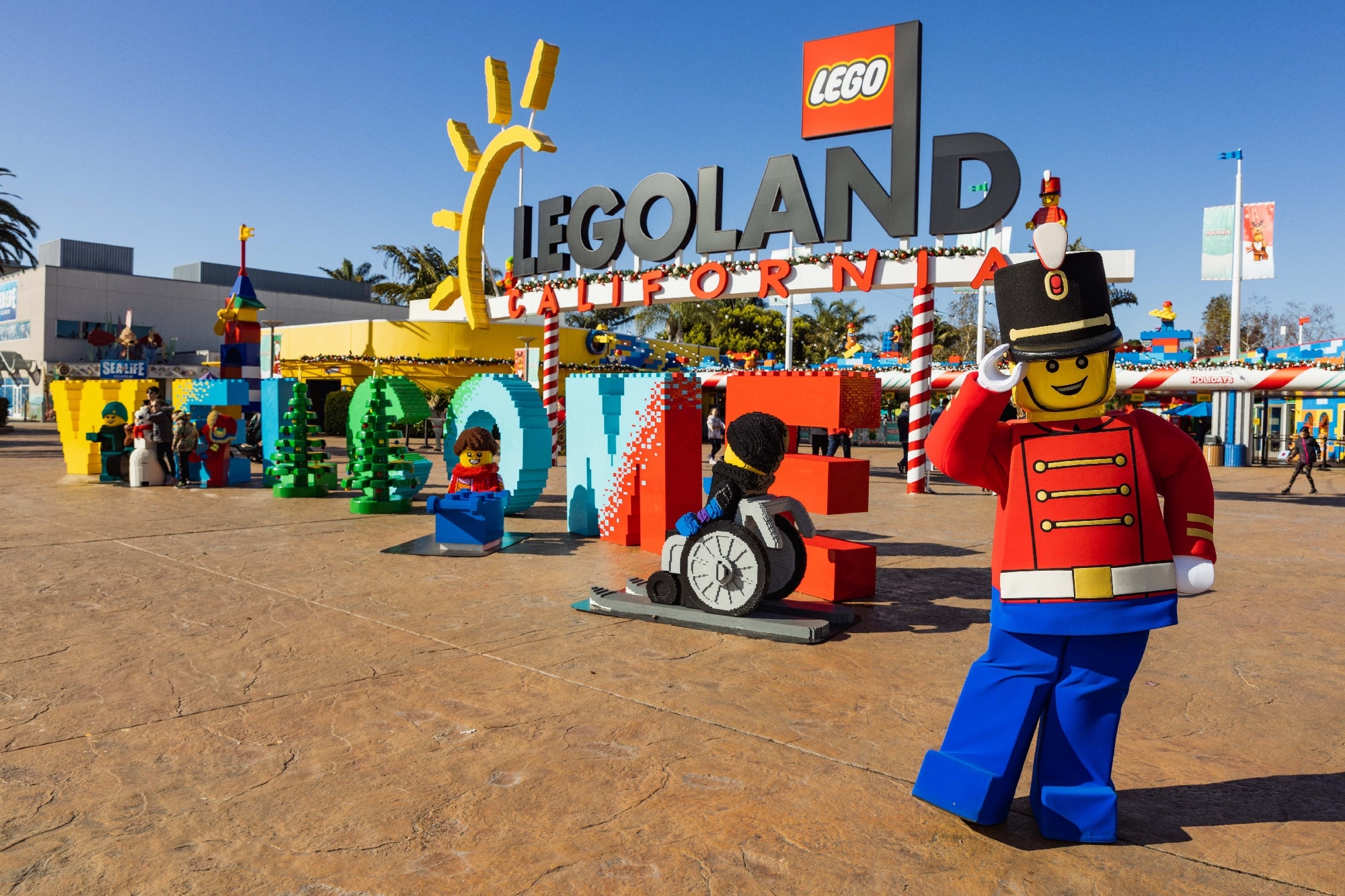 LEGOLAND California entrance with colorful LEGO sculptures and a life-sized LEGO figure dressed as a toy soldier greeting visitors.