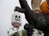 A large LEGO sculpture of a hand holding a lantern shaped like a white jack-o’-lantern, displayed outdoors with a cloudy sky in the background.