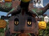 Close-up of a large tree made from LEGO bricks, with yellow eyes and hanging jack-o'-lantern decorations, set outdoors.