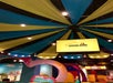 The colorful interior of a LEGOLAND Discovery Center, featuring a striped ceiling, a screen announcing "Now Showing 4D LEGO Movies," and a yellow and blue cloth decor.