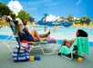 A family relaxing on lounge chairs by a water park, enjoying their time together while children play in the pool in the background.