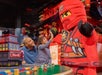 A little girl with her dad giving a LEGO ninja a high five at LEGOLAND® Discovery Center in Columbus, Ohio.