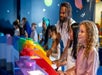 A line of several parents and children playing games and smiling at LEGO Discovery Center Boston.