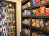 Shelves display various snacks and personal care items, including chips, gum, and hygiene products.