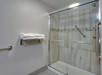 A bathroom with a glass-enclosed shower featuring beige tiles and a towel rack with neatly folded white towels.