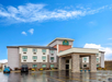 Exterior view of a La Quinta Inn & Suites hotel with a covered entrance, parking lot, and several cars under a blue sky.