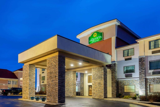 Hotel entrance with a stone exterior and covered driveway, under a blue evening sky.