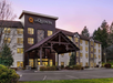 La Quinta hotel building with a wooden entrance canopy, surrounded by trees and grass, under a twilight sky.