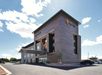 Four-story La Quinta hotel building with distinct brown exterior under a blue sky, featuring a sun logo and a sleek entrance canopy.