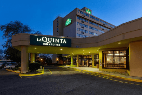 La Quinta Inn & Suites building at dusk with illuminated signage and entrance.
