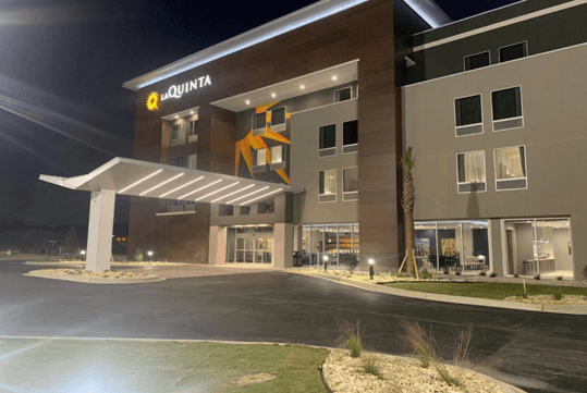 The front exterior of the La Quinta Inn & Suites by Wyndham Valdosta with a covered entrance on a clear night.