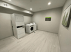 A laundry area with gray walls, a stack of dryers, and two washers side by side at the La Quinta Inn & Suites by Wyndham Valdosta.