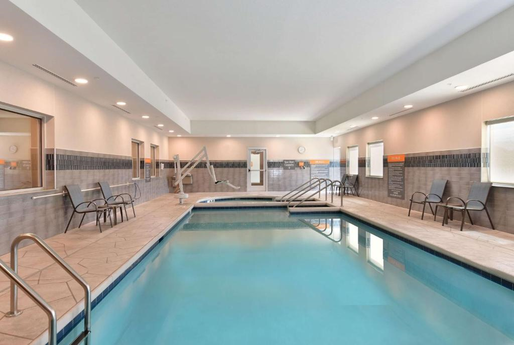 Indoor swimming pool with seating chairs along the sides and light gray tiled walls.