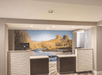 Two white and dark brown front desks with computers at them and a photo of the Red Rocks on the wall behind them.