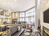 A modern lounge area and dining room with floor to ceiling windows, several dining tables, couches, chair, and a fireplace.