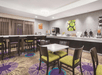 A dining room with a several tables and chairs and a full breakfast bar on the cabinets along the wall at the La Quinta by Wyndham in New Braunfels, Texas.