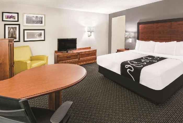 One king bed, a flat-screen TV, an armchair and a work desk inside a non-smoking room.