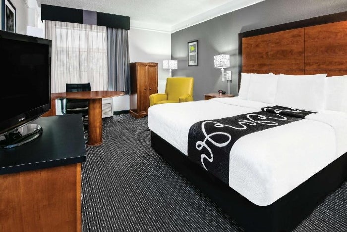 One king bed, a flat-screen TV, an armchair and a work desk inside a non-smoking room.
