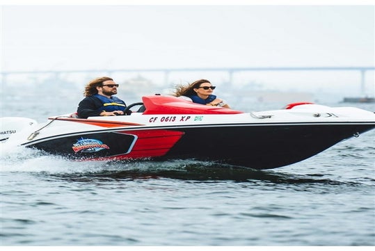 A man and woman in a white, red and black speed boat with the wind blowing their hair back on the Land and Sea: GoCar Tour + Speed Boat Adventure.