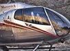 A silver and red Maverick Airbus helicopter featuring its wrap-around glass for outstanding visibility with rocks in the background.