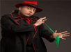 Bizzaro in a black suit with red accents performing a trick with a green scarf at Late Night Magic Las Vegas.