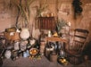 A rustic room with various ceramic pots, baskets of fruit, a wooden chair, a candle, sugarcane, and vintage furniture against a worn brick wall.