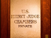 Frosted glass door with gold lettering that reads "U.S. District Judge Chambers Private.