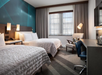 Guest room with two queen beds, work desk, and arm chair.