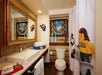 A bathroom with a sink, mirror, toilet, towels, and toiletries; the shower curtain features a LEGO mermaid, and the decor includes pirate-themed artwork and accents.