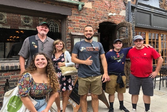 The tour guide wearing Philly Crawling shirt and the guests smiling at Liberty Pub Crawl of Philadelphia