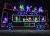 Neon light display of a double-decker tour bus with animated figures on both levels and the words "Tour NYC!" written on the side.